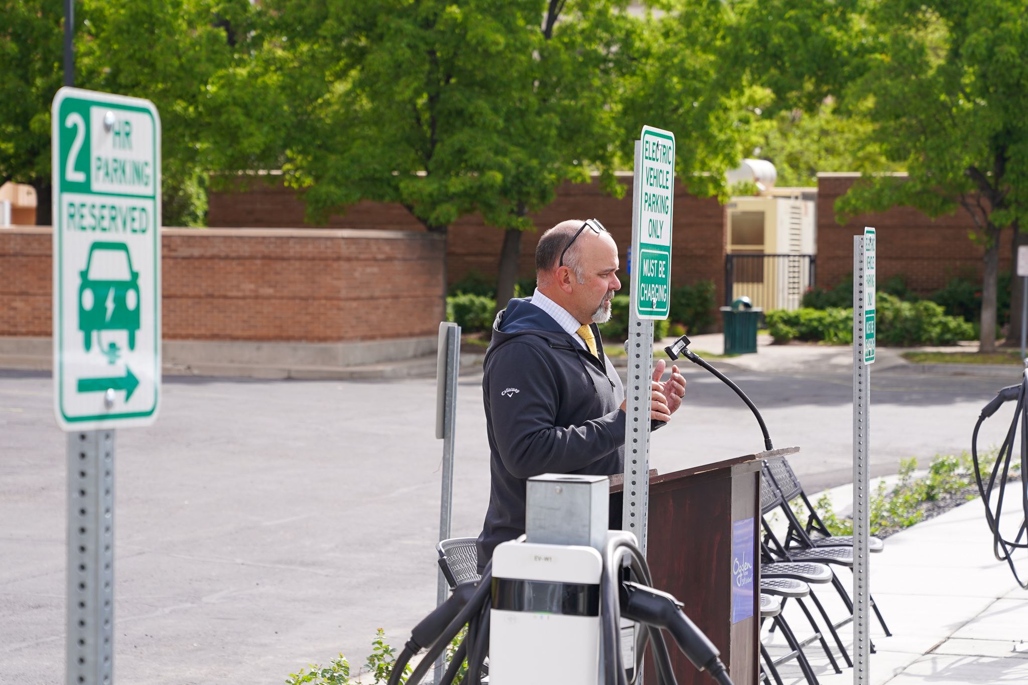 A man at a podium, next to the new EV charging stations